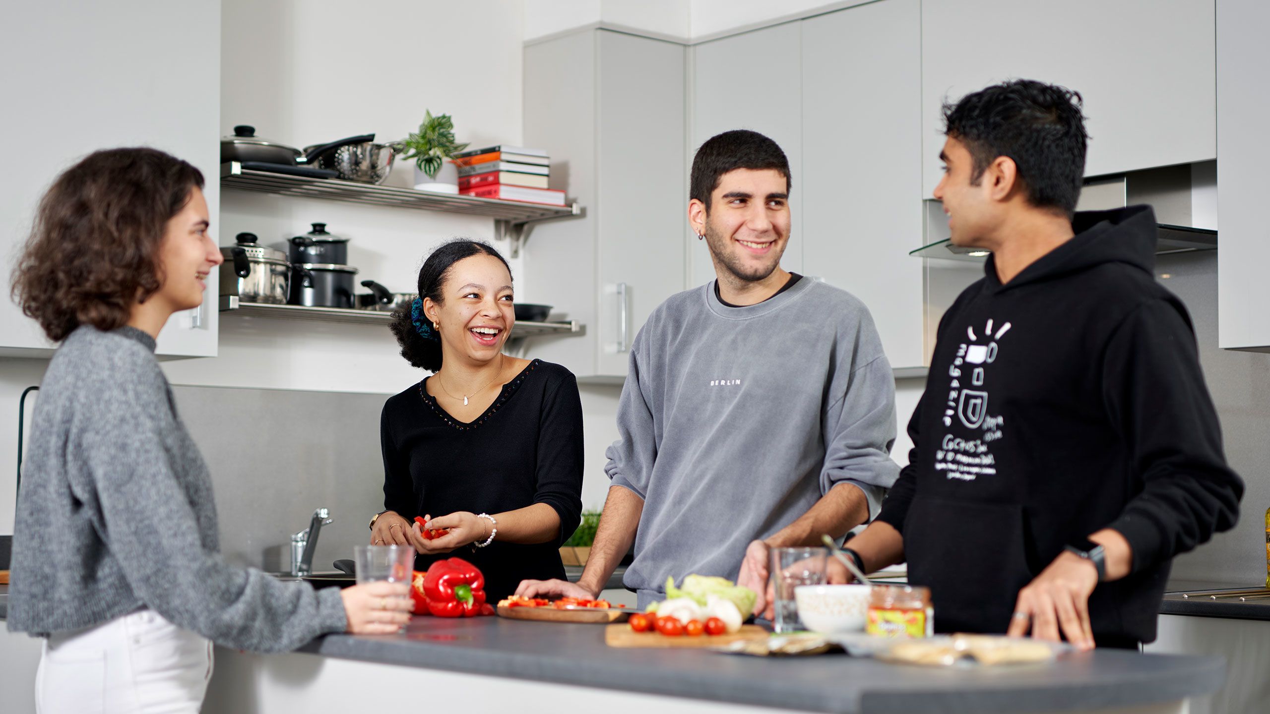 A group of students preparing food round a kitchen worktop
