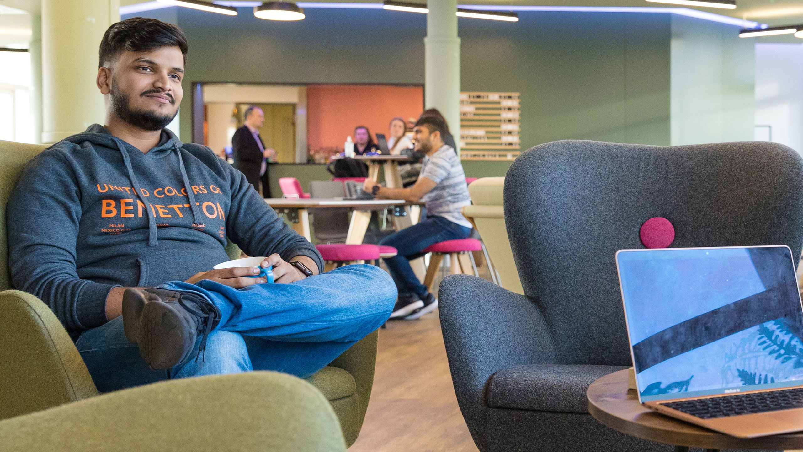 A student relaxes in an easy chair with a hot drink