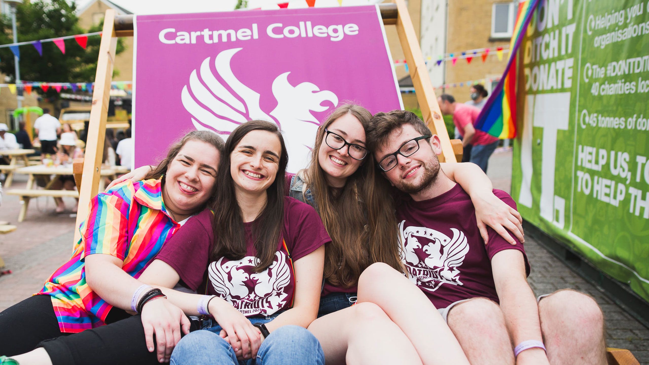 Students sitting in a giant deckchair branded with their college