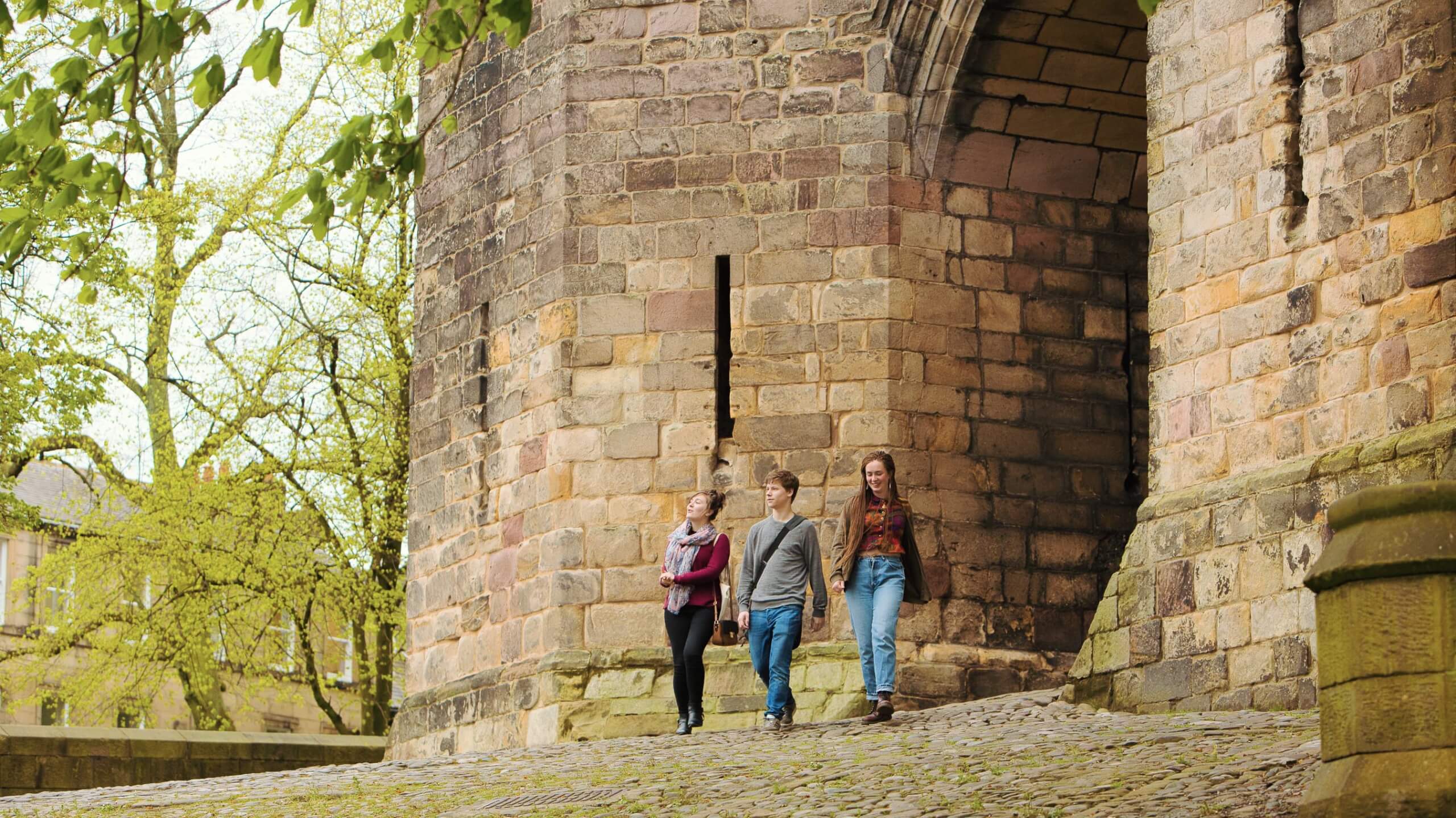 Three students walk by Lancaster Castle.
